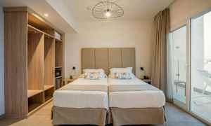 Kaksi erillistä sänkyä, joissa beige pääty ja yöpöydät kummallakin puolella. (Tekoälyn luoma teksti)