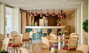 Valoisa ja moderni sisällä sijaitseva baari, jossa on baarijakkarat ja pöytiä ympäriinsä. (Tekoälyn luoma teksti)