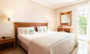 Hotellihuone, jossa on parivuode, puukalusteet ja parvekkeen ovi. (Tekoälyn luoma teksti)