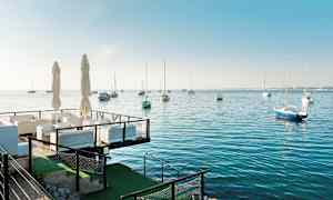 Ulkoilmaravintola meren äärellä ja purjeveneitä vedessä. (Tekoälyn luoma teksti)