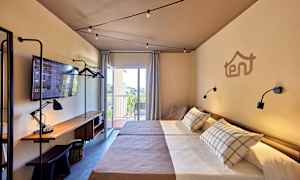 Hotellihuone, jossa on kaksi erillistä vuodetta, työpöytä lampulla ja televisio sekä parveke näkymällä. (Tekoälyn luoma teksti)