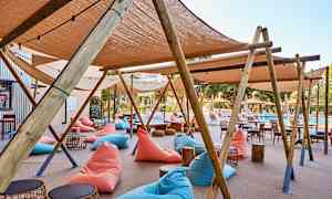 Ulkotila aurinkotuoleilla, puukalusteilla ja lepotuoleilla uima-altaan lähellä. (Tekoälyn luoma teksti)