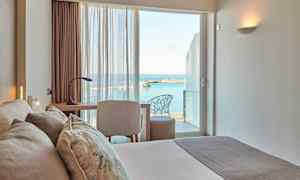 Hotellihuone, josta on näkymä merelle ikkunan läpi. (Tekoälyn luoma teksti)