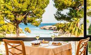 Kattaus ruoalla ja kahdella viinilasilla, näkymä merelle suuren ikkunan kautta. (Tekoälyn luoma teksti)