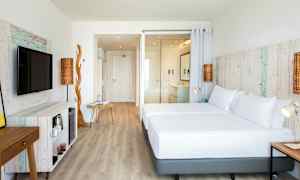 Vaalea hotellihuone, jossa on puuyksityiskohtia ja nykyaikaiset huonekalut. Huoneessa on suuri sänky, televisio ja avoin pohjaratkaisu. (Tekoälyn luoma teksti)