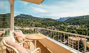 Ulkokalusteet parvekkeella, näkymä vehreään laaksoon ja vuoriin taustalla. (Tekoälyn luoma teksti)