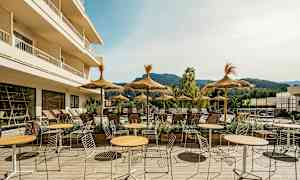 Ulkona oleva alue, jossa pöytiä, tuoleja ja aurinkovarjoja aurinkoisella terassilla. (Tekoälyn luoma teksti)