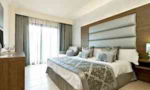 Moderni makuuhuone, jossa on parisänky, pehmustettu sängyn pääty ja koristellut tekstiilit. Suuret lasiovet, joissa on vaaleat verhot. (Tekoälyn luoma teksti)