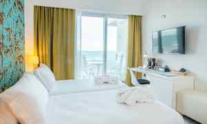 Hotellihuone, jossa kaksi sänkyä, työpöytä, seinä-TV ja merinäkymä parvekkeelta. (Tekoälyn luoma teksti)