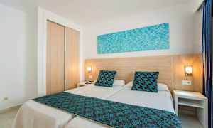 Hotellihuone, jossa kaksi erillistä vuodetta ja sinisiä yksityiskohtia. (Tekoälyn luoma teksti)