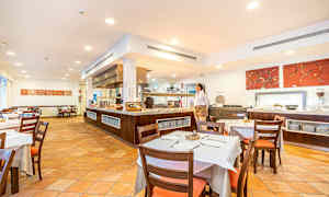 Kuva tilavasta ravintolasta, jossa on katettuja pöytiä ja tarjoilutiski. (Tekoälyn luoma teksti)