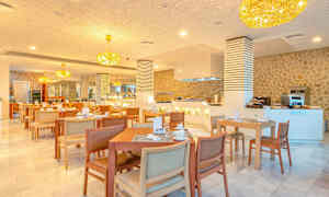 Ravintola, jossa on pöytiä ja tuoleja, kattokruunuja katossa ja tarjoilutiski. (Tekoälyn luoma teksti)