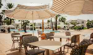 Ulkouima-allasalue, jossa on aurinkotuoleja, varjoja ja pöytiä tuoleilla. (Tekoälyn luoma teksti)