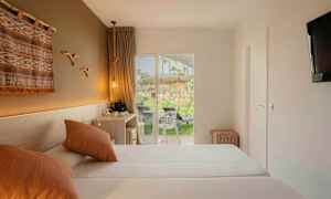 Hotellihuone, jossa on kaksi sänkyä, koristeellinen seinäkoriste ja terassi, jolta on näkymä viheralueelle. (Tekoälyn luoma teksti)