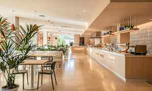 Valoisa ja moderni ruokailualue, jossa on pöytiä, tuoleja ja buffetpöytiä. (Tekoälyn luoma teksti)