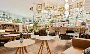 Moderni ja tyylikkäästi sisustettu kahvila, jossa istumaryhmiä ja kasveja. (Tekoälyn luoma teksti)