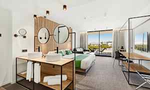 Moderni hotellihuone, jossa on parivuode, istuimet ja kylpyhuoneen osa. (Tekoälyn luoma teksti)