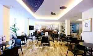 Moderni sisätila, jossa on mustia pöytiä ja tuoleja, koristekasveja ja valoisa ilmapiiri. (Tekoälyn luoma teksti)