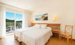 Hotellihuone, jossa on kaksi erillistä vuodetta, parveke ja maisemakuva seinällä. (Tekoälyn luoma teksti)