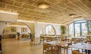 Ravintolan sisustus, jossa on kivikaari, nykyaikaiset huonekalut ja koristekasveja. (Tekoälyn luoma teksti)