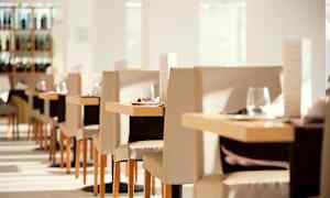Valoisan ja tyylikkään ravintolan sisustus, jossa on katettuja pöytiä ja tuoleja. (Tekoälyn luoma teksti)