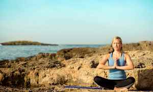 Henkilö harjoitusvaatteissa istuu meditaatioasennossa kalliolla meren äärellä. (Tekoälyn luoma teksti)