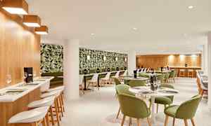 Ravintolan sisustus, jossa on vihreät tuolit ja kasviaiheinen tapettikuosi. (Tekoälyn luoma teksti)