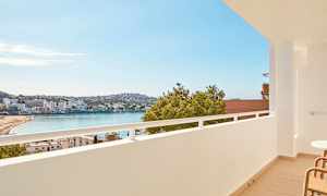 Näkymä parvekkeelta rannalle lahden äärellä, taustalla rakennuksia ja vihreitä alueita. (Tekoälyn luoma teksti)