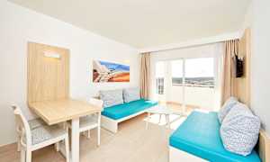 Olohuone, jossa kaksi sinistä sohvaa, pöytä ja tuolit sekä parveke näkymällä. (Tekoälyn luoma teksti)