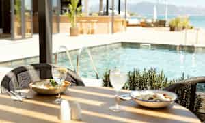 Ruokapöytä uima-altaan vieressä, jossa kaksi annosta ja juomia. (Tekoälyn luoma teksti)