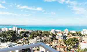 Näkymä rantakaupungista, jossa rakennuksia, puita ja meri taustalla. (Tekoälyn luoma teksti)