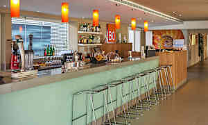 Moderni baaritiski, jossa on baarituoleja sekä pulloja ja laseja hyllyllä ja tasolla. (Tekoälyn luoma teksti)