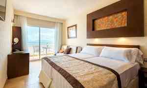 Hotellihuone, jossa on parivuode, kirjoituspöytä ja parveke näkymällä. (Tekoälyn luoma teksti)