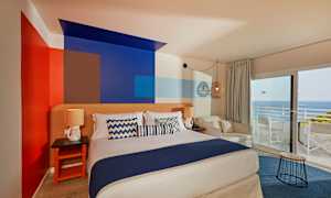 Huone, jossa on parivuode, koristeellisesti maalatut seinät, istuinpaikat ja näkymä merelle suurten ikkunoiden kautta. (Tekoälyn luoma teksti)