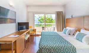 Hotellihuone, jossa kaksi sänkyä, työpöytä ja ikkuna näkymällä parvekkeelle. (Tekoälyn luoma teksti)