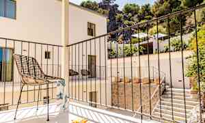 Parveke, jossa on tuoli ja kaide, ympärillä rakennus ja viheralueita. (Tekoälyn luoma teksti)