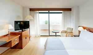 Hotellihuone kahdella sängyllä, televisio puukomuutilla ja lasiovi, joka johtaa terassille. (Tekoälyn luoma teksti)