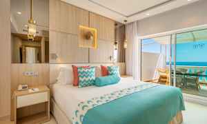 Hotellihuone, jossa on parivuode, sisustettu sinisellä ja valkoisella, ja näkymä merelle parvekkeelta. (Tekoälyn luoma teksti)