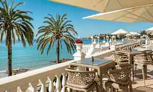 Terassi, jolta näkyy meri, aurinkotuoleja ja varjoja. (Tekoälyn luoma teksti)