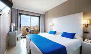 Hotellihuone, jossa parivuode, vaaleat seinät ja siniset vuodevaatteet. (Tekoälyn luoma teksti)