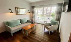 Istumaryhmä, jossa on sohvapöytä ja tuoleja, sekä lasi-ikkuna, josta pääsee parvekkeelle. (Tekoälyn luoma teksti)