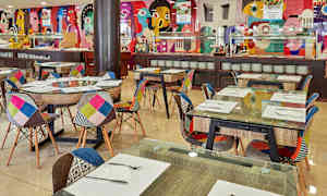 Ravintolan sisustus, jossa on värikkäitä tuoleja ja koristeltuja seiniä. (Tekoälyn luoma teksti)