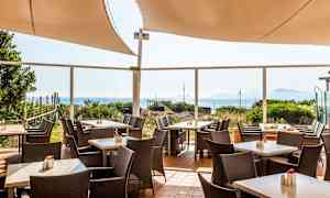 Kuva ulkoterassista, jossa pöydät, tuolit ja merinäköala. (Tekoälyn luoma teksti)