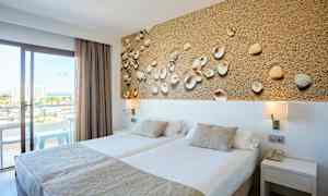 Hotellihuone, jossa on kaksi erillistä vuodetta, koristeellinen taulu simpukoilla ja parveke näkymällä. (Tekoälyn luoma teksti)