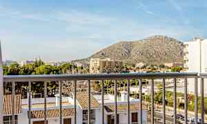 Näkymä parvekkeelta, jossa näkyy rakennuksia tiilikatoilla ja ympäröivää kaupunkimaisemaa, taustalla vuori. (Tekoälyn luoma teksti)