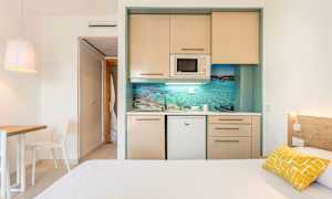 Yksinkertainen hotellihuone, jossa on pieni keittiö ja sänky. (Tekoälyn luoma teksti)