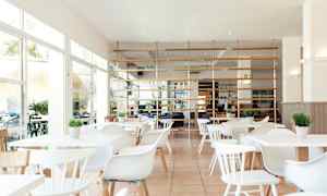 Valoisa ja moderni ravintola, jossa valkoiset huonekalut ja vihreitä kasveja. (Tekoälyn luoma teksti)