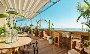 Terassi, jossa puutarhakalusteita ja kasveja, näkymä merelle. (Tekoälyn luoma teksti)