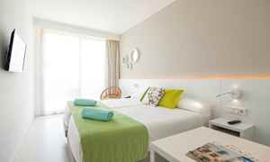 Moderni hotellihuone, jossa kaksi erillistä sänkyä ja vihreitä yksityiskohtia. (Tekoälyn luoma teksti)