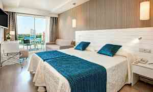 Hotellihuone, jossa on kaksi sänkyä, sohva ja lasiparveke. (Tekoälyn luoma teksti)